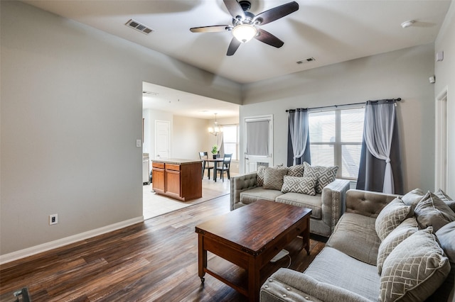 living room featuring ceiling fan with notable chandelier and light hardwood / wood-style flooring