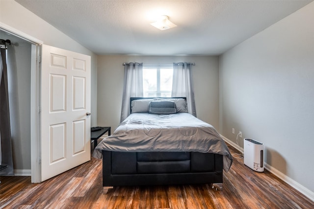 bedroom featuring vaulted ceiling, dark wood-type flooring, and a textured ceiling