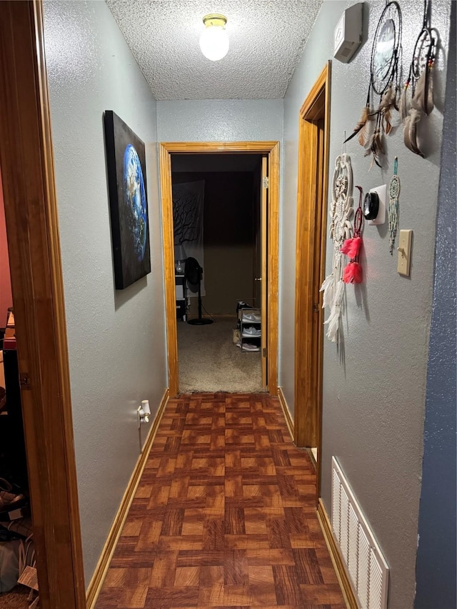 hallway with dark parquet flooring and a textured ceiling