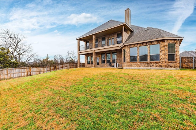 back of house with a yard and a balcony