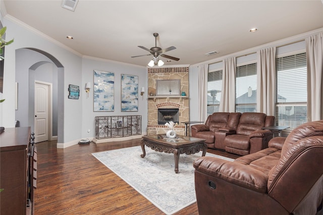 living room with ornamental molding, a healthy amount of sunlight, dark wood-type flooring, and a fireplace