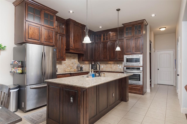 kitchen with decorative light fixtures, sink, a kitchen island with sink, stainless steel appliances, and dark brown cabinets