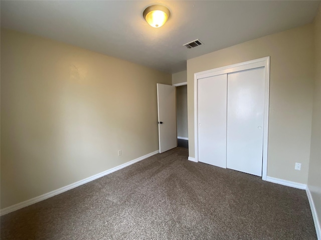 unfurnished bedroom featuring a closet and dark colored carpet