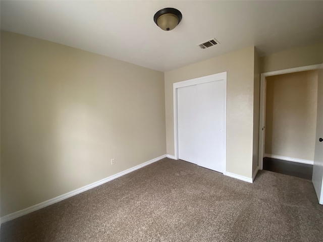 unfurnished bedroom featuring a closet and dark colored carpet