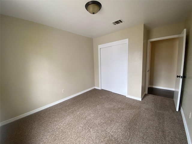 unfurnished bedroom with a closet and dark colored carpet