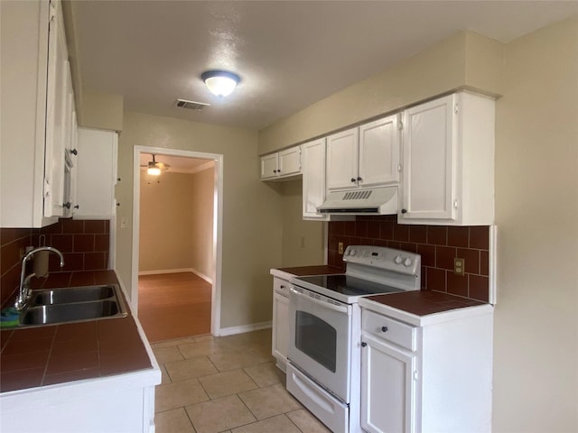 kitchen with white electric range, sink, white cabinetry, tile counters, and decorative backsplash