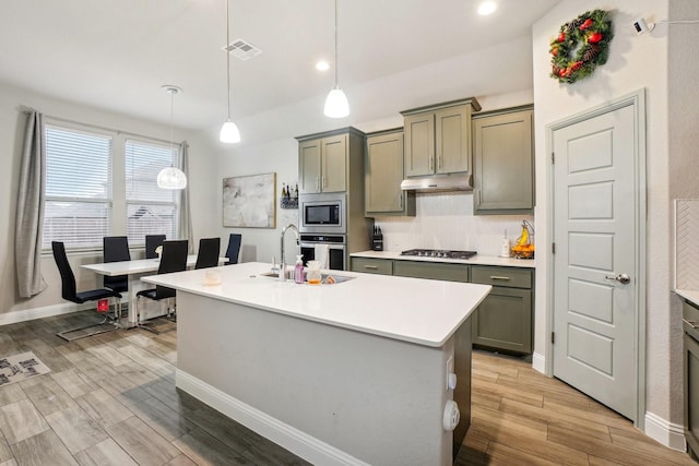 kitchen featuring hanging light fixtures, a center island with sink, sink, and appliances with stainless steel finishes