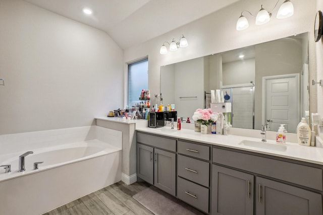 bathroom featuring vanity, hardwood / wood-style floors, lofted ceiling, and independent shower and bath