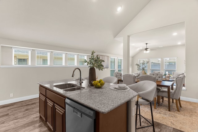 kitchen with dishwasher, lofted ceiling, sink, a breakfast bar area, and a center island with sink