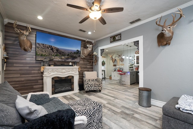 living room with ornamental molding, light hardwood / wood-style floors, and ceiling fan