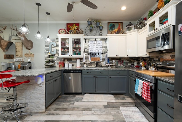 kitchen featuring white cabinetry, gray cabinets, stainless steel appliances, and a kitchen bar