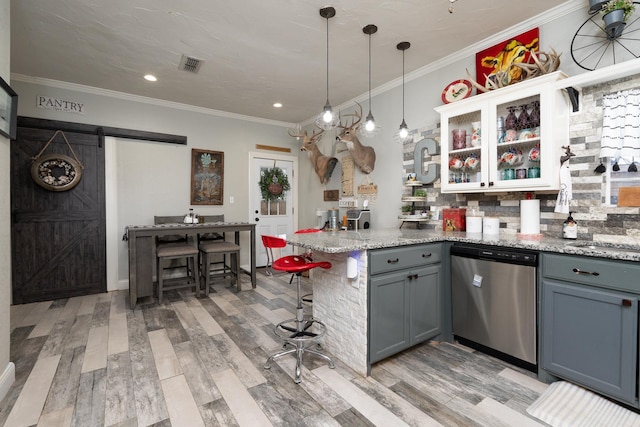 kitchen with a breakfast bar, hanging light fixtures, light stone counters, stainless steel dishwasher, and a barn door