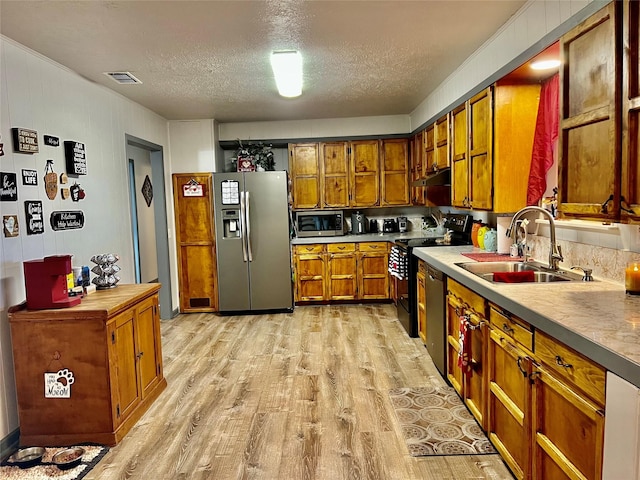 kitchen with a textured ceiling, sink, light hardwood / wood-style flooring, and black appliances