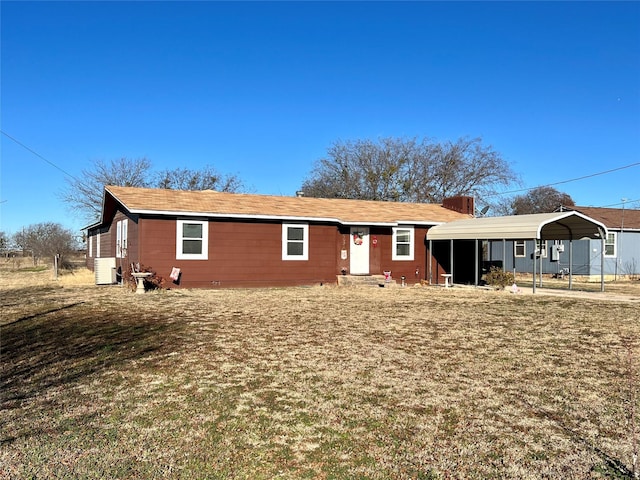 rear view of property featuring central AC unit, a lawn, and a carport