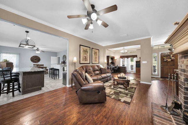 living room featuring a fireplace, crown molding, ceiling fan with notable chandelier, and dark hardwood / wood-style floors