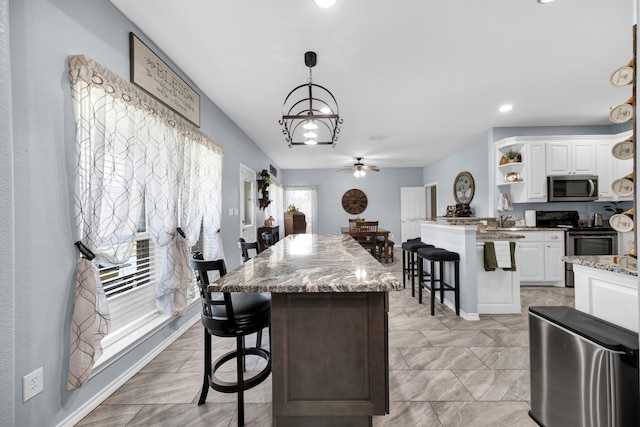 kitchen with white cabinetry, appliances with stainless steel finishes, a kitchen breakfast bar, and pendant lighting