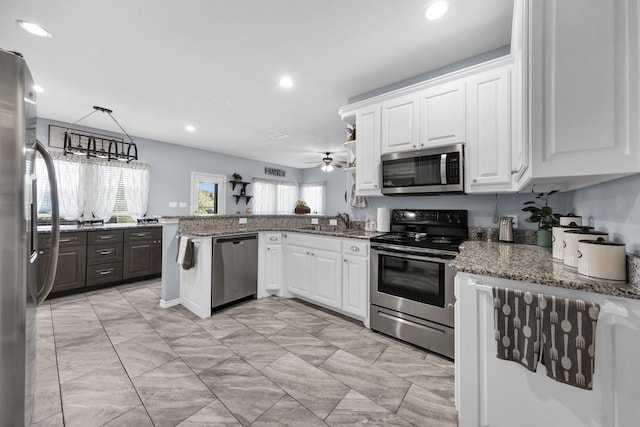 kitchen featuring sink, white cabinetry, hanging light fixtures, appliances with stainless steel finishes, and kitchen peninsula