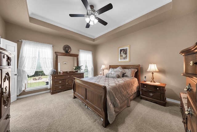 carpeted bedroom with a raised ceiling and ceiling fan