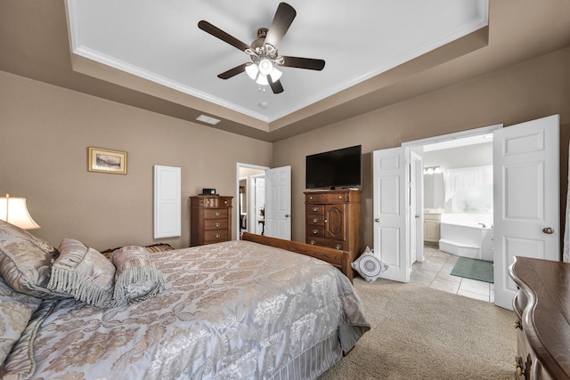 carpeted bedroom featuring a tray ceiling, ornamental molding, ceiling fan, and ensuite bathroom