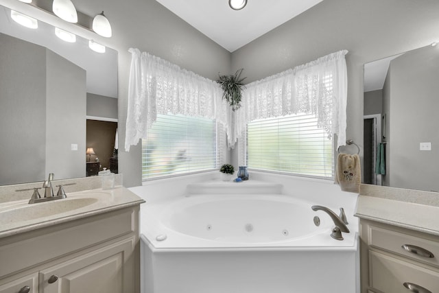 bathroom featuring a tub to relax in, vanity, and plenty of natural light