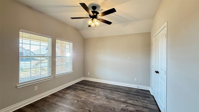 spare room featuring dark wood-type flooring, vaulted ceiling, and ceiling fan