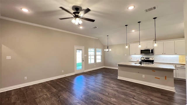 kitchen with pendant lighting, lofted ceiling, appliances with stainless steel finishes, white cabinetry, and a center island with sink