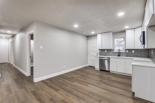 kitchen with dark wood-type flooring, sink, appliances with stainless steel finishes, white cabinets, and backsplash