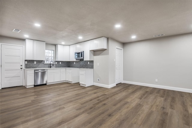 kitchen featuring white cabinetry, appliances with stainless steel finishes, dark hardwood / wood-style floors, and tasteful backsplash