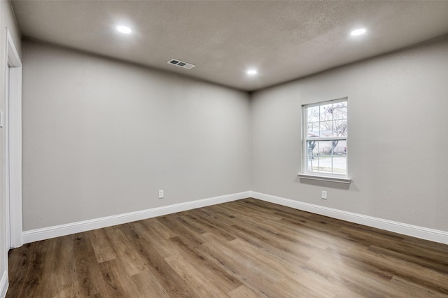 unfurnished room featuring wood-type flooring and a textured ceiling