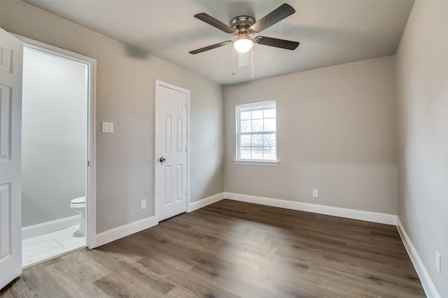 unfurnished bedroom with wood-type flooring, ceiling fan, and ensuite bath