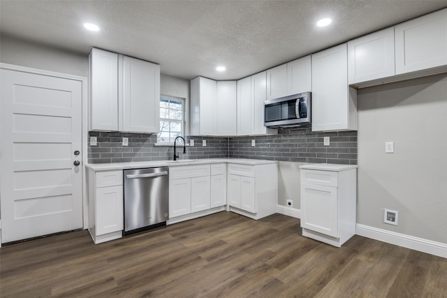 kitchen featuring dark hardwood / wood-style floors, tasteful backsplash, white cabinetry, sink, and stainless steel appliances