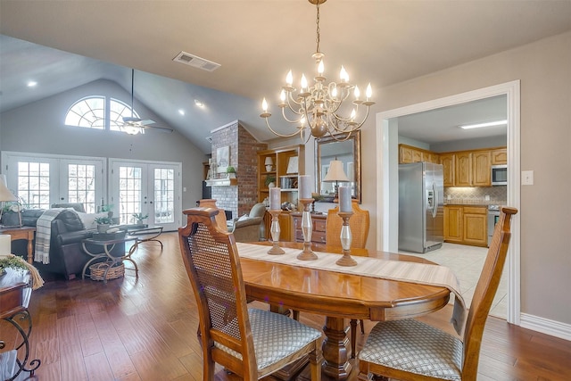 dining area with vaulted ceiling, ceiling fan with notable chandelier, light hardwood / wood-style flooring, and french doors