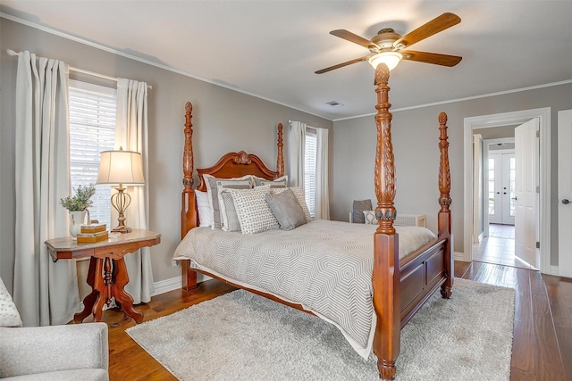 bedroom featuring dark wood-type flooring, ceiling fan, crown molding, and multiple windows