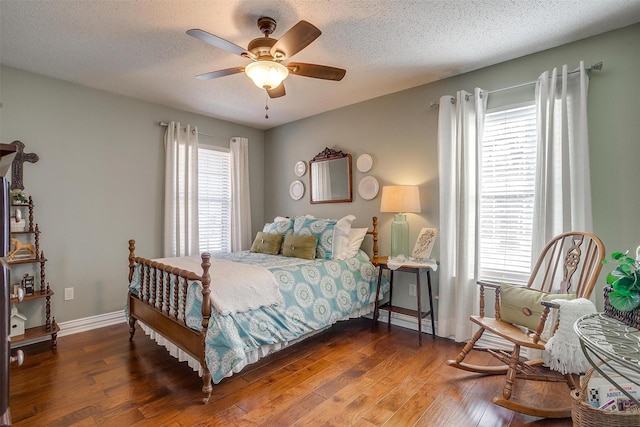 bedroom with multiple windows, ceiling fan, dark wood-type flooring, and a textured ceiling