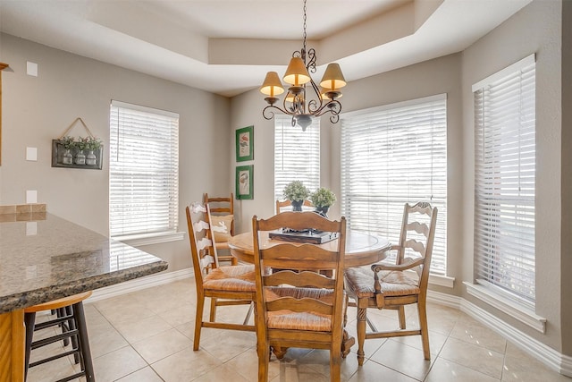 dining room featuring an inviting chandelier, light tile patterned floors, and a raised ceiling