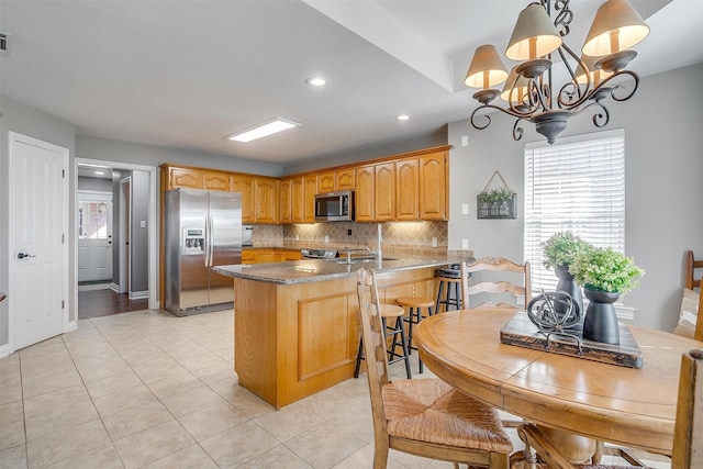 kitchen featuring light tile patterned floors, stainless steel appliances, tasteful backsplash, a notable chandelier, and kitchen peninsula