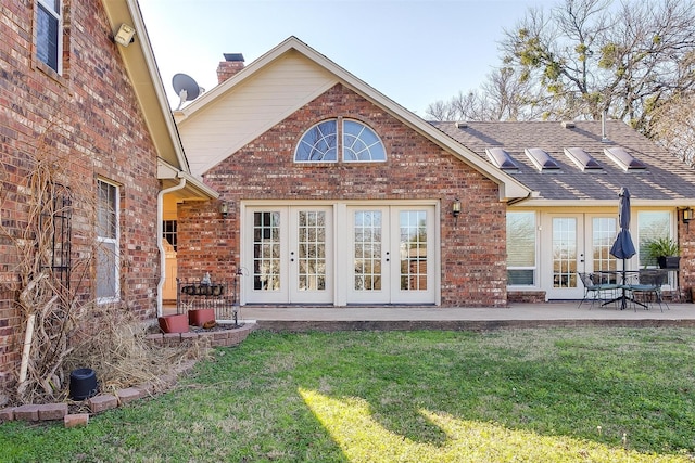 rear view of property featuring a patio, a lawn, and french doors