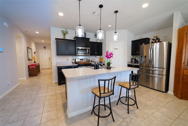 kitchen featuring light tile patterned flooring, pendant lighting, a kitchen breakfast bar, a kitchen island with sink, and stainless steel appliances