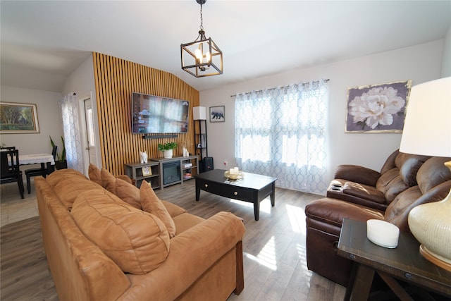 living room with an inviting chandelier, vaulted ceiling, and wood-type flooring