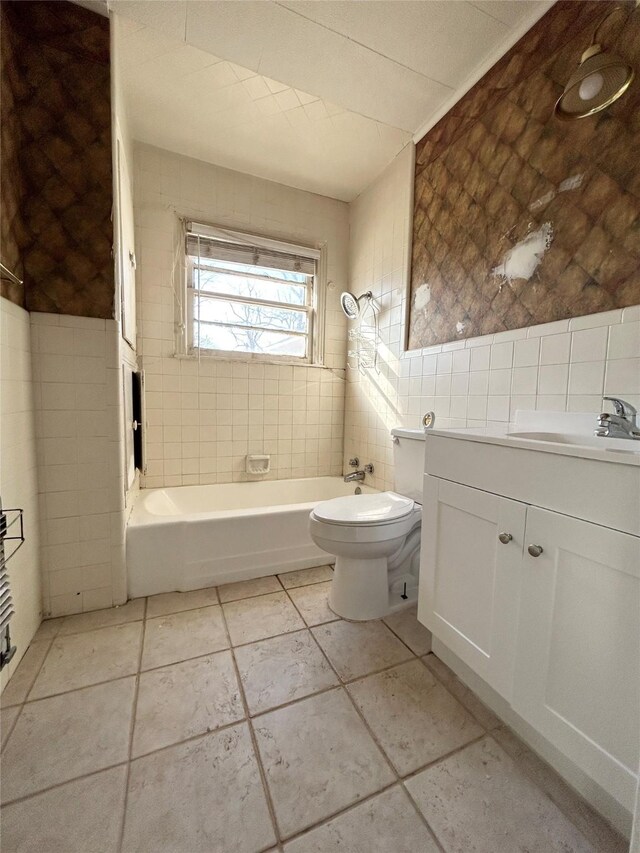 full bathroom featuring tile walls, vanity, toilet, and tiled shower / bath