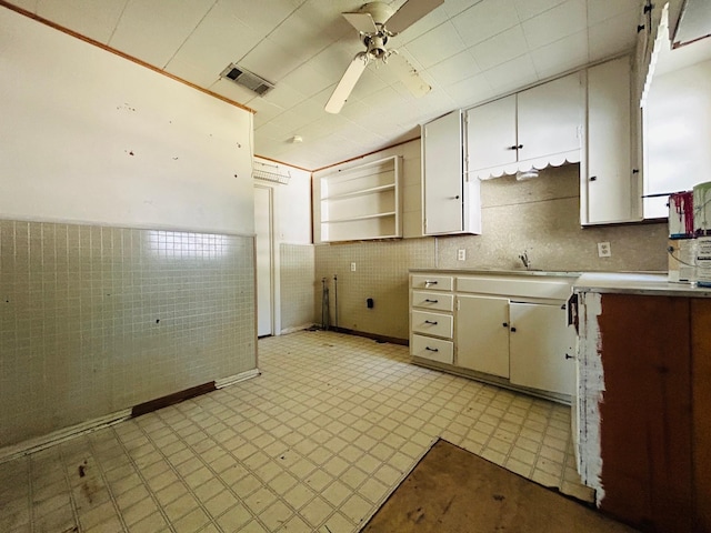 kitchen with tile walls, ceiling fan, sink, and white cabinets