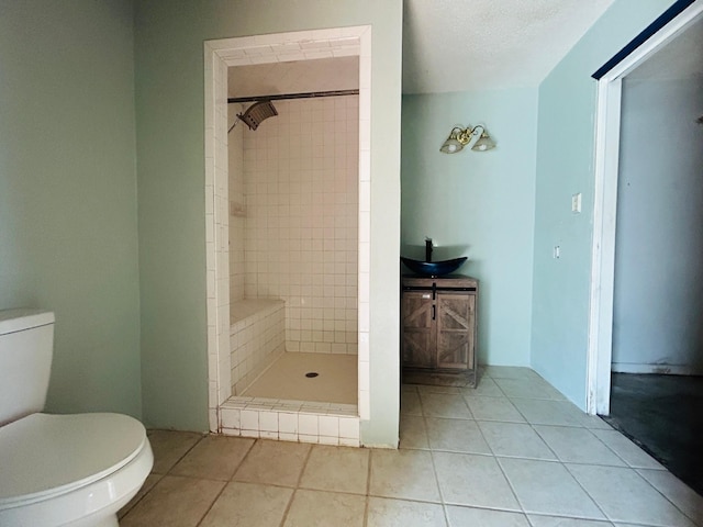 bathroom with vanity, tile patterned floors, toilet, and tiled shower