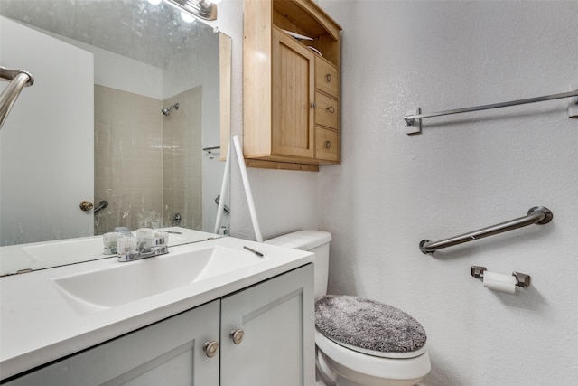 bathroom with vanity, toilet, and a tile shower