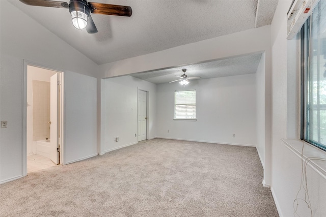 spare room with ceiling fan, vaulted ceiling, light carpet, and a textured ceiling