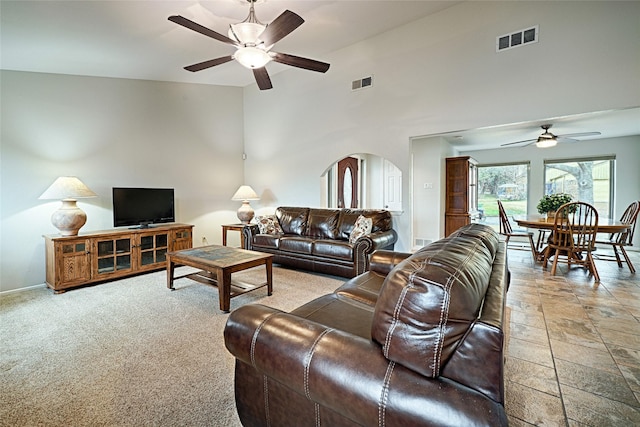 living room featuring a towering ceiling, baseboards, visible vents, and arched walkways