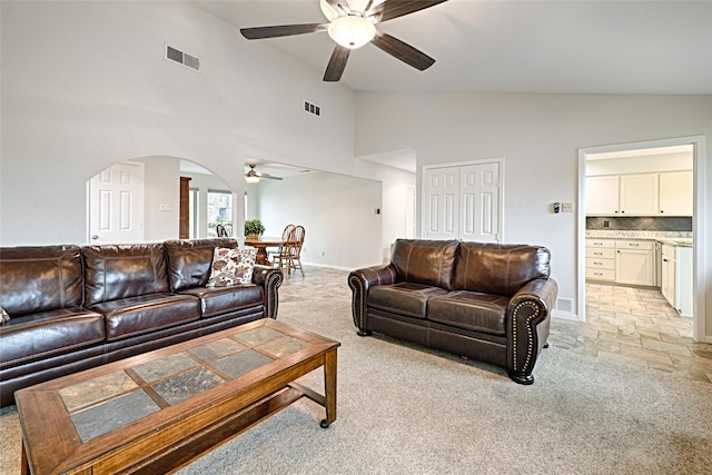 living area featuring a ceiling fan, arched walkways, visible vents, and light carpet