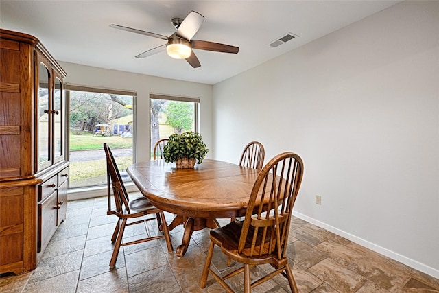 dining area with ceiling fan, stone tile flooring, visible vents, and baseboards