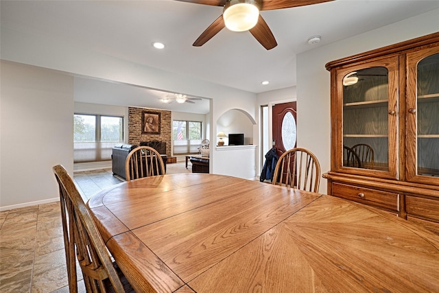 unfurnished dining area with ceiling fan, a fireplace, baseboards, and recessed lighting