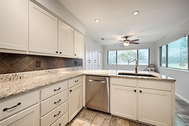 kitchen featuring light stone countertops, a peninsula, a sink, decorative backsplash, and dishwasher