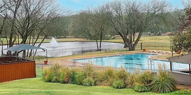 pool with a yard, a water view, and fence